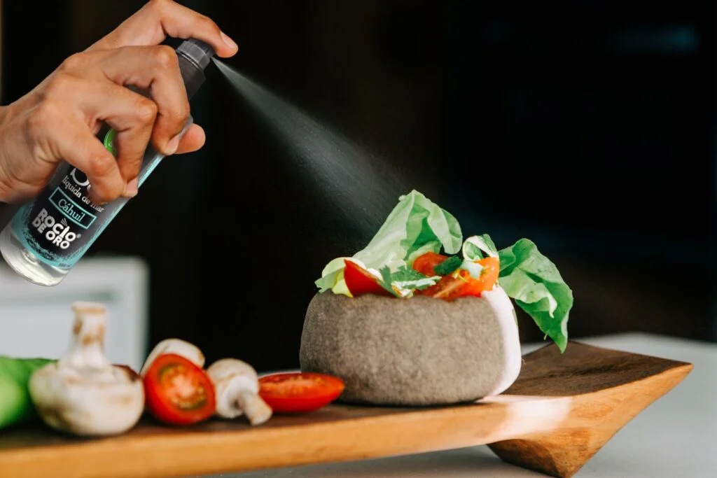 Nuestro producto consiste en un aderezo líquido en base a sal de mar de Cáhuil, reducido en sodio, envasado en una botella PET (Tereftalato de Polietileno) de 150ml, el cual es un material plástico sanitario, no tóxico, reciclable, con un tiempo de degradación inferior al vidrio, ampliamente usado en envases para la industria de alimentos-, con una tapa con bomba de spray o atomizador, lo que permite una innovadora y práctica forma de dosificación por atomización, ideal para ser usado como sazonador o aderezo en todo tipo de alimentos y preparaciones, especialmente en ensaladas, carnes, pescados, mariscos, guisos, sopas, entre otros.